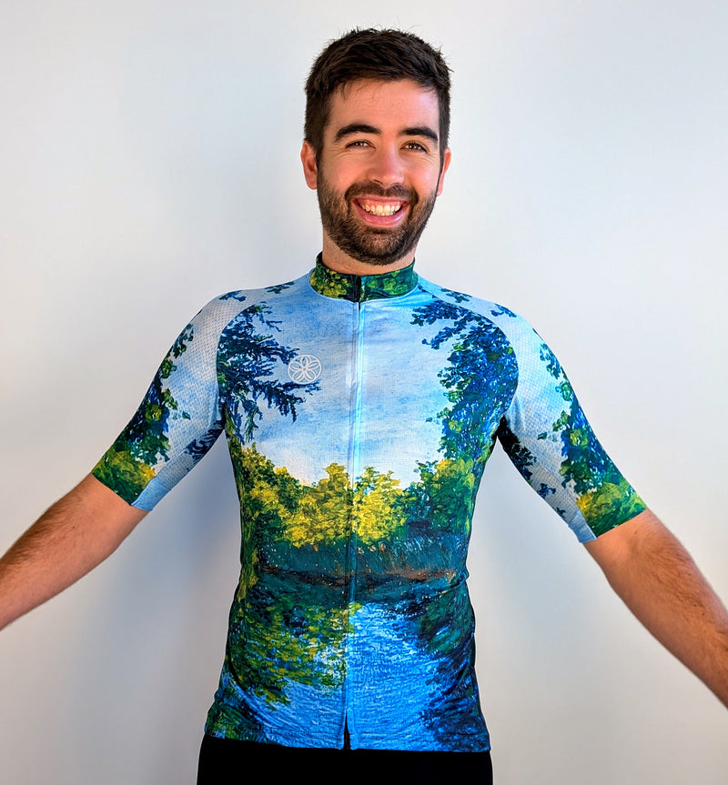 Man wearing a colorful cycling jersey with a nature-themed design on a plain background